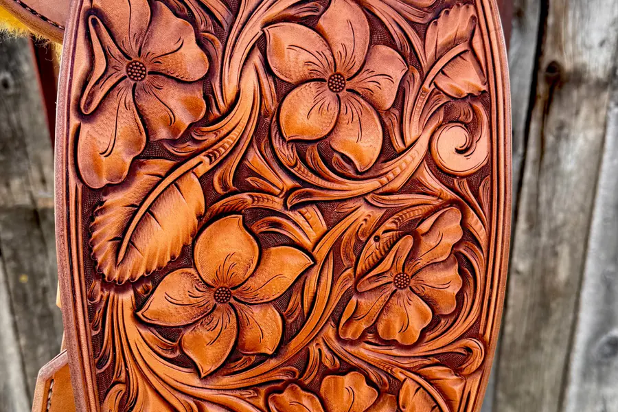 Hand-carved flowers and leaves on a saddle fender
