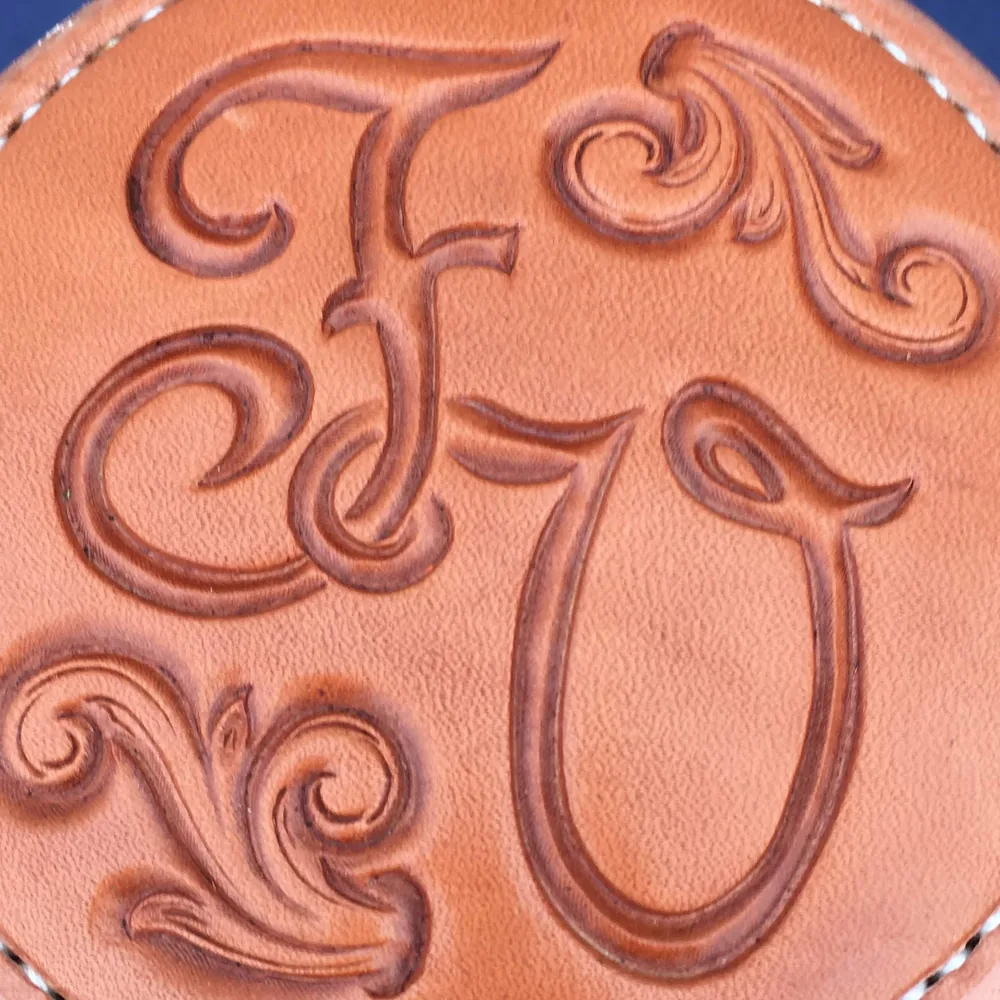 Hand-carved initials and scrollwork on the back of a saddle cantle