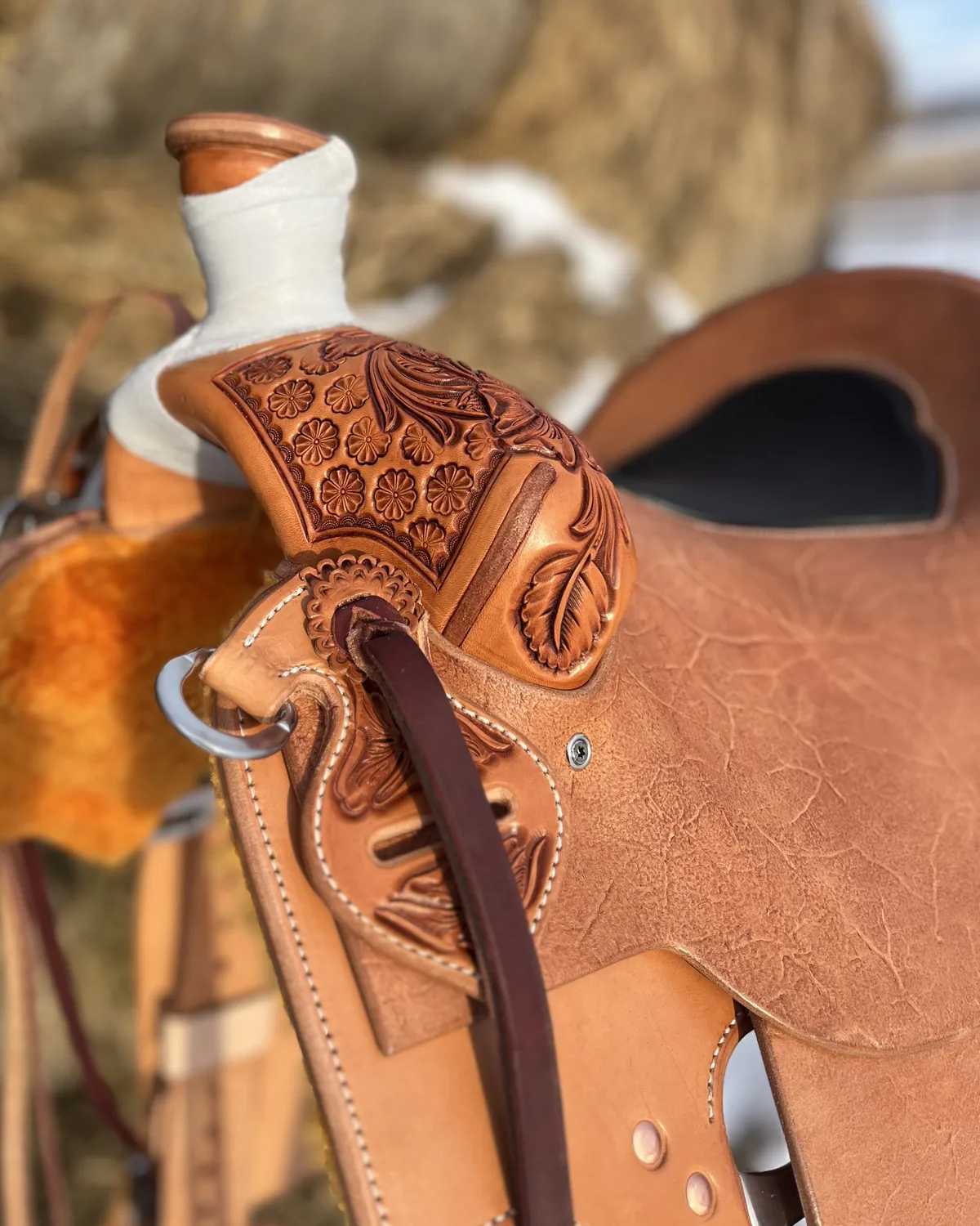 Tooled saddle resting on a hay bale