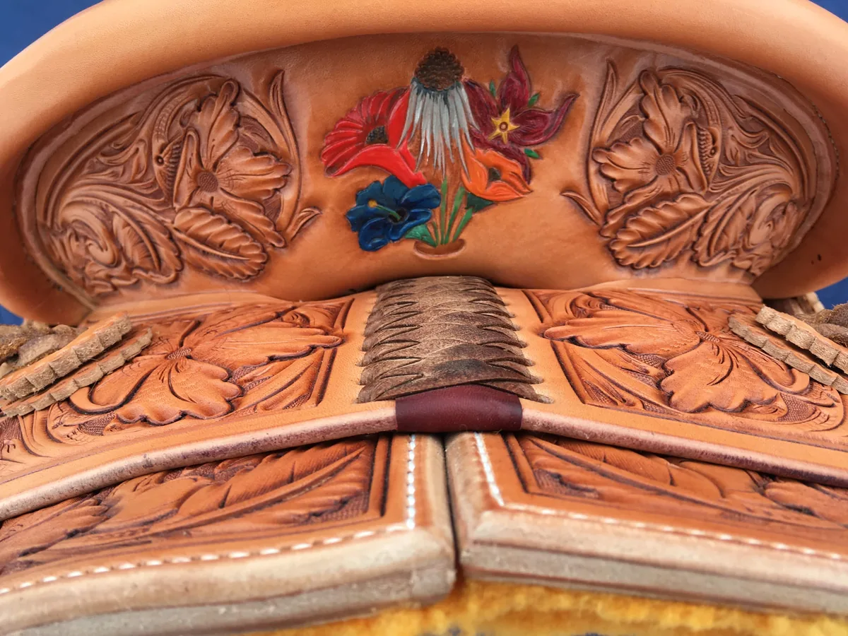 Saddle seat with colour-tinted floral carving across the jockeys