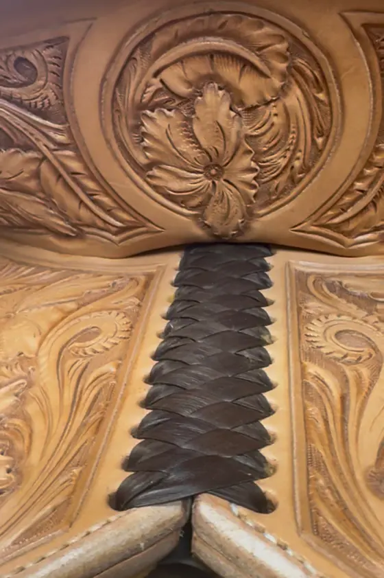 Braided leather lacing running down the back of a hand-carved saddle cantle