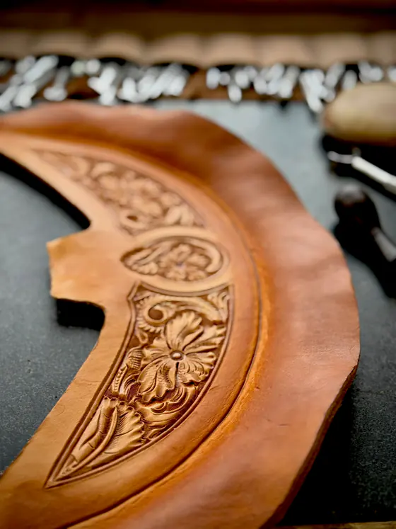A freshly carved cantle piece lying on the bench in front of a rack of stamping tools