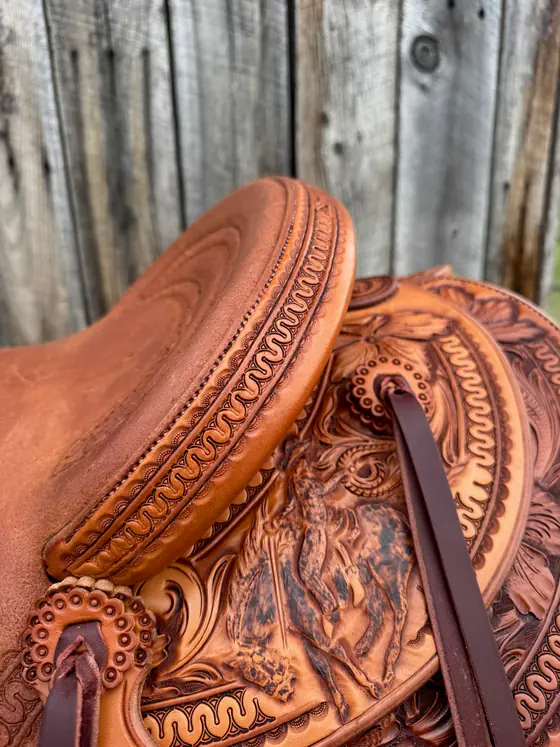 Figure carving with wood-burned shading set among tooled borders on a saddle