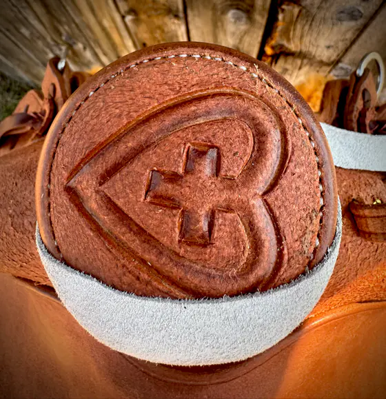 Saddle horn cap stamped with a heart-and-cross ranch brand