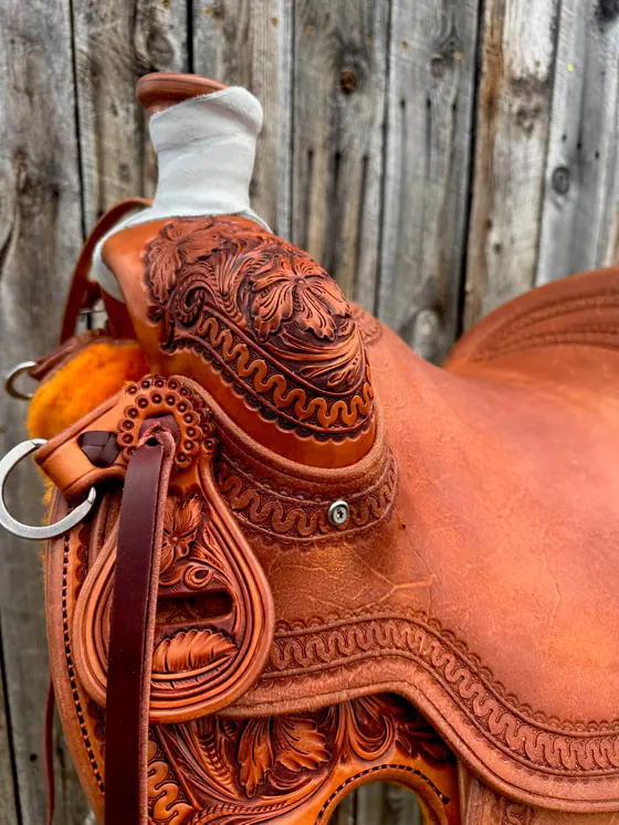 Detail of hand-stamped border work and carved leaves on a finished saddle