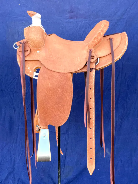 Plain roughout swell-fork custom saddle against a blue backdrop