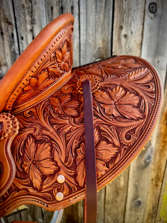 Hand-carved Sheridan-style floral tooling across a saddle seat and jockeys