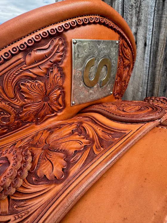 Engraved silver initial plate mounted on the cantle of a hand-carved custom saddle