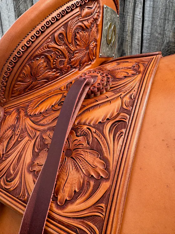 Silver-mounted saddle seat with hand-carved floral tooling and engraved silver corner plate