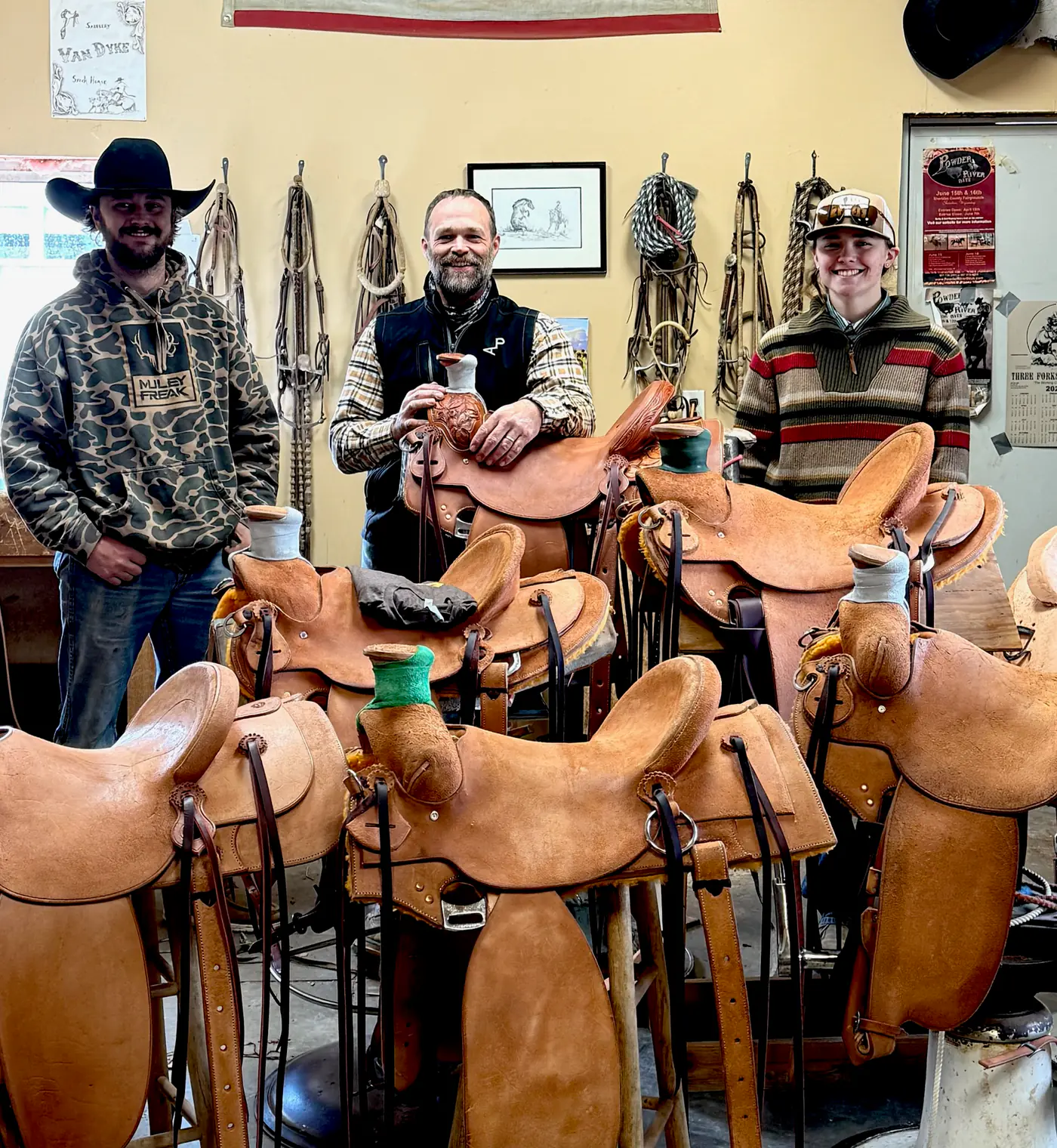 Paul Van Dyke and two students in a shop full of student-built saddles